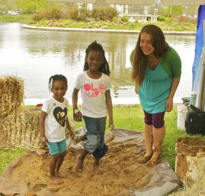 Author Josi shows some budding young natural builders how to stomp plaster. Photo by Ashly.