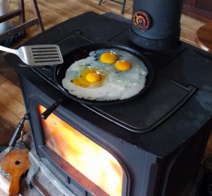 'Tis the season for cooking with a wood fire at Dancing Rabbit. Dennis prepares to flip his eggs while heating the house. Photo by Dennis.
