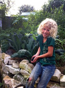 Against a backdrop of kale, Aurelia shows some of the black raspberries her mom harvested. Photo by Ted.